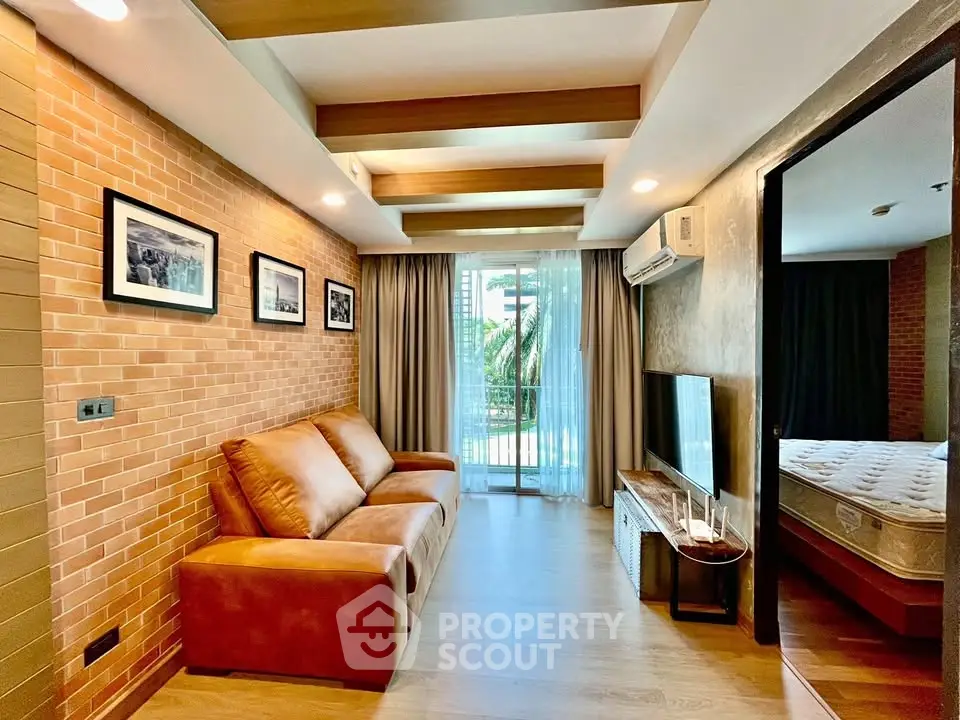 Stylish living room with leather sofa and modern decor, featuring a view of the balcony and bedroom access.