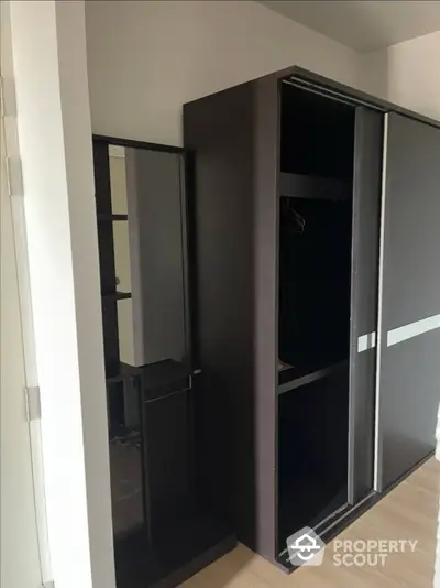 Sleek modern bedroom with spacious built-in wardrobe featuring mirrored sliding doors, offering a stylish storage solution in a contemporary home.