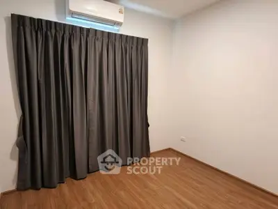 Spacious empty room with wooden flooring and air conditioning, perfect for customization.