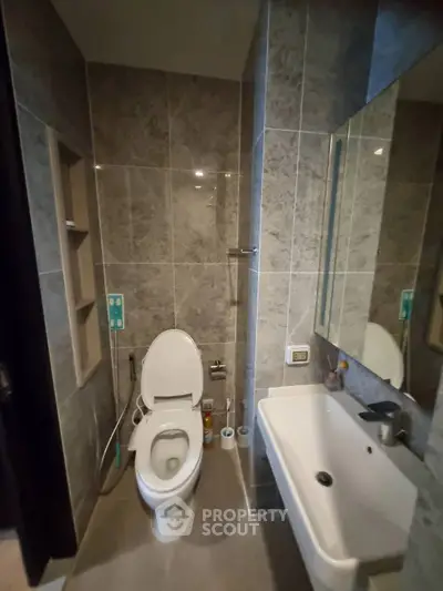 Modern bathroom with sleek fixtures and elegant tile design, featuring a toilet and sink.