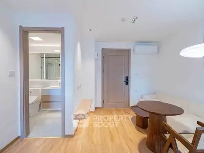 Modern living room with wooden flooring and cozy furniture adjacent to a sleek bathroom.