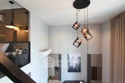 Modern loft-style living room with high ceiling and unique pendant lighting.