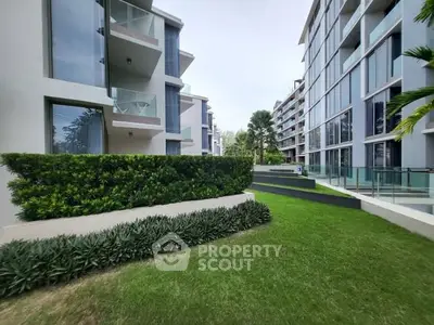 Modern apartment complex with lush green landscaping and glass balconies