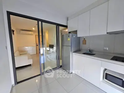 Modern kitchen with sleek cabinetry and open layout leading to a cozy living room.