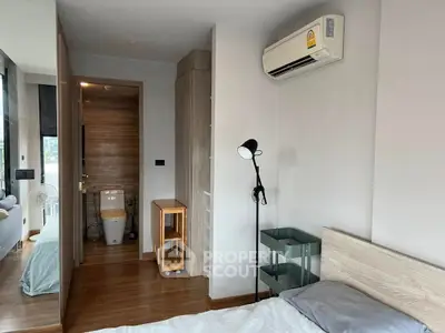 Modern bedroom with air conditioning and wooden flooring, featuring a cozy bed and stylish decor.