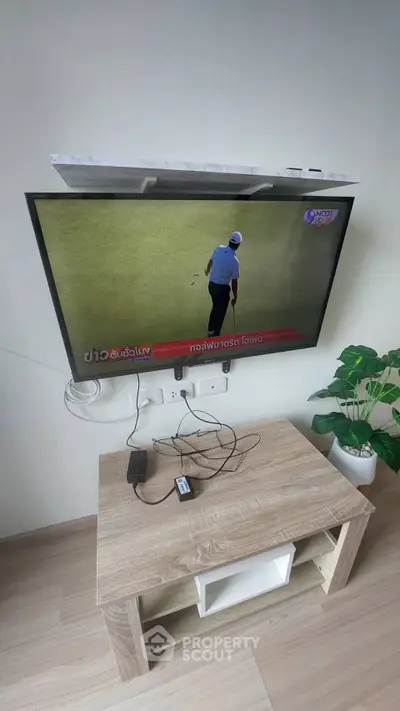 Modern living room with wall-mounted TV and stylish wooden console table.