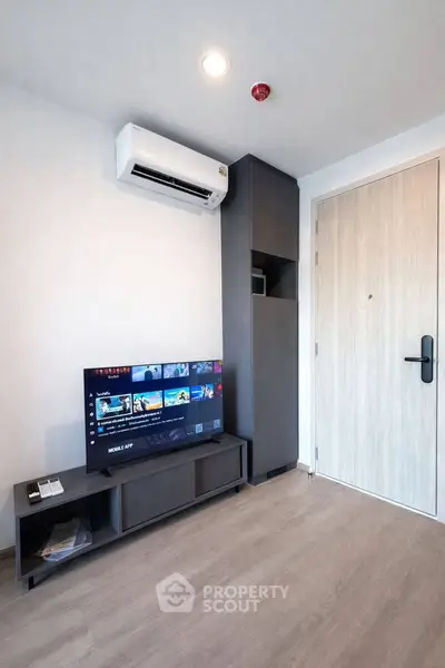 Modern living room with sleek TV setup and air conditioning in a stylish apartment.