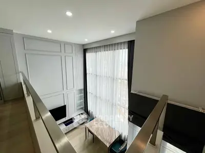 Modern loft-style living room with high ceilings and large windows