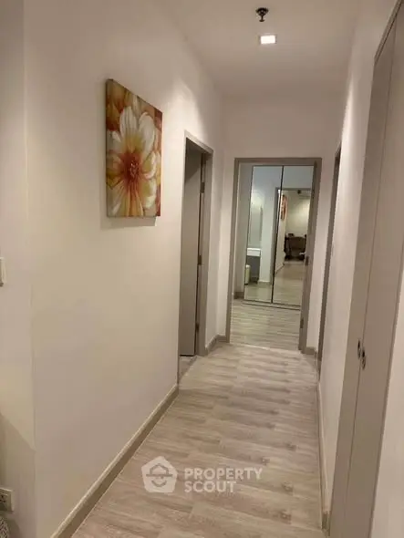 Modern hallway with wooden flooring and floral wall art in a stylish apartment.