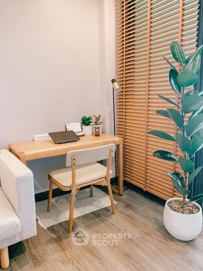 Cozy study nook with wooden desk, chair, and potted plant in modern apartment.