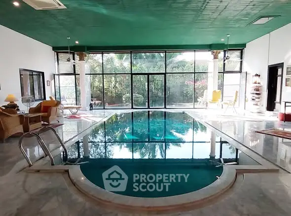 Luxurious indoor pool with elegant seating and lush garden view, perfect for relaxation and entertainment.