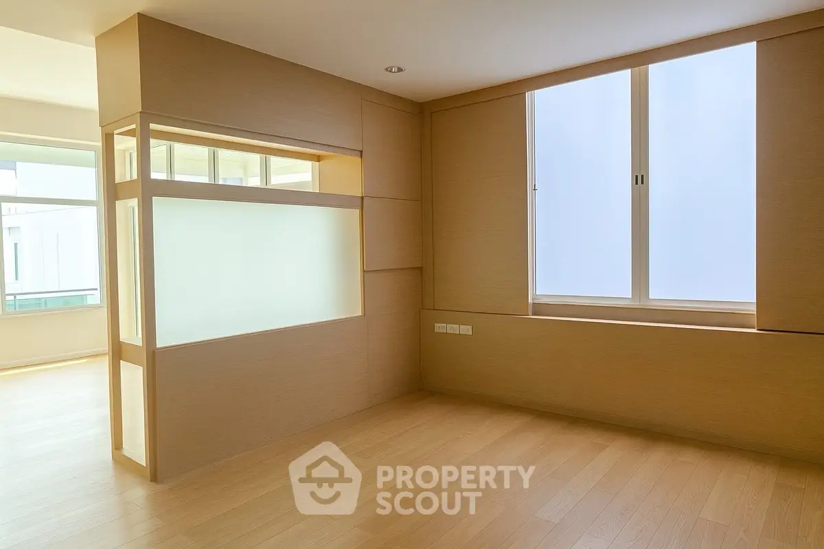 Spacious modern room with large window and wooden flooring, perfect for versatile interior design.