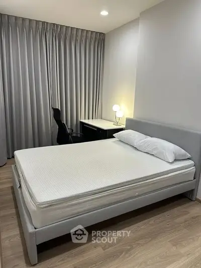Modern bedroom with sleek design, featuring a comfortable bed and a stylish desk with a lamp.