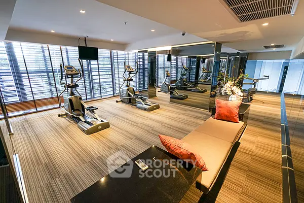 Spacious modern gym with exercise machines and large windows in luxury apartment complex.