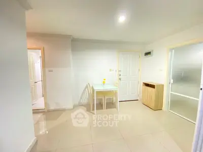 Bright and airy modern apartment interior with a compact dining area, pristine tiled flooring, and a sleek kitchenette, ideal for urban living.