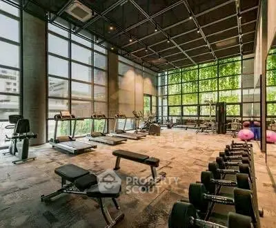 Spacious modern gym with large windows and fitness equipment in luxury building.