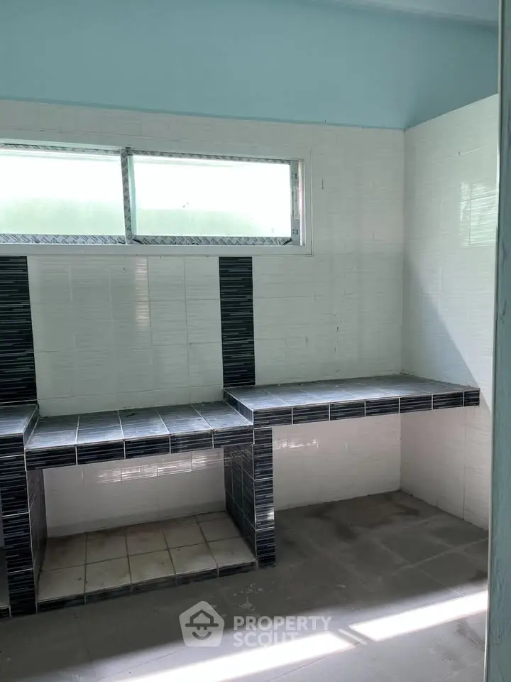 Spacious tiled kitchen area with modern design and ample natural light.