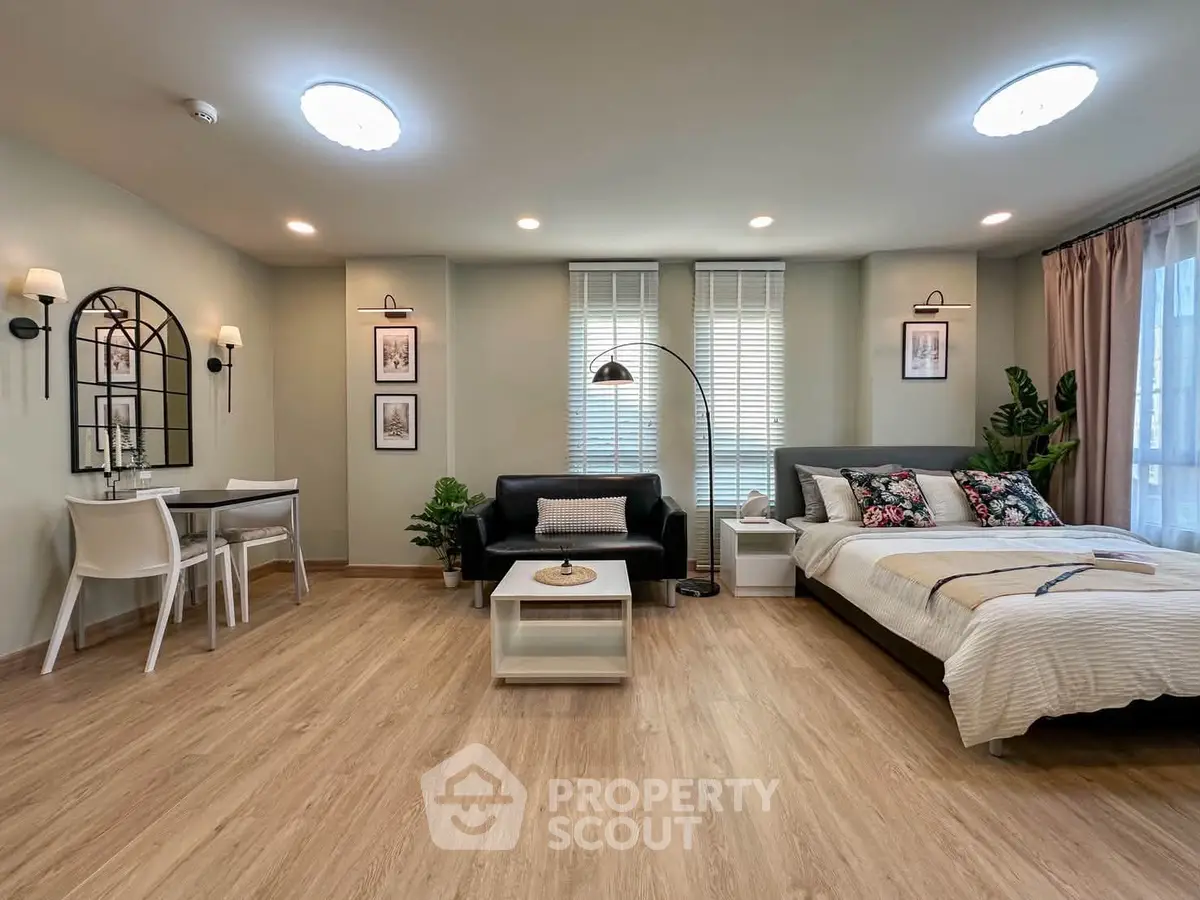 Modern studio apartment with stylish decor, featuring a cozy bed, chic sofa, and elegant dining area.