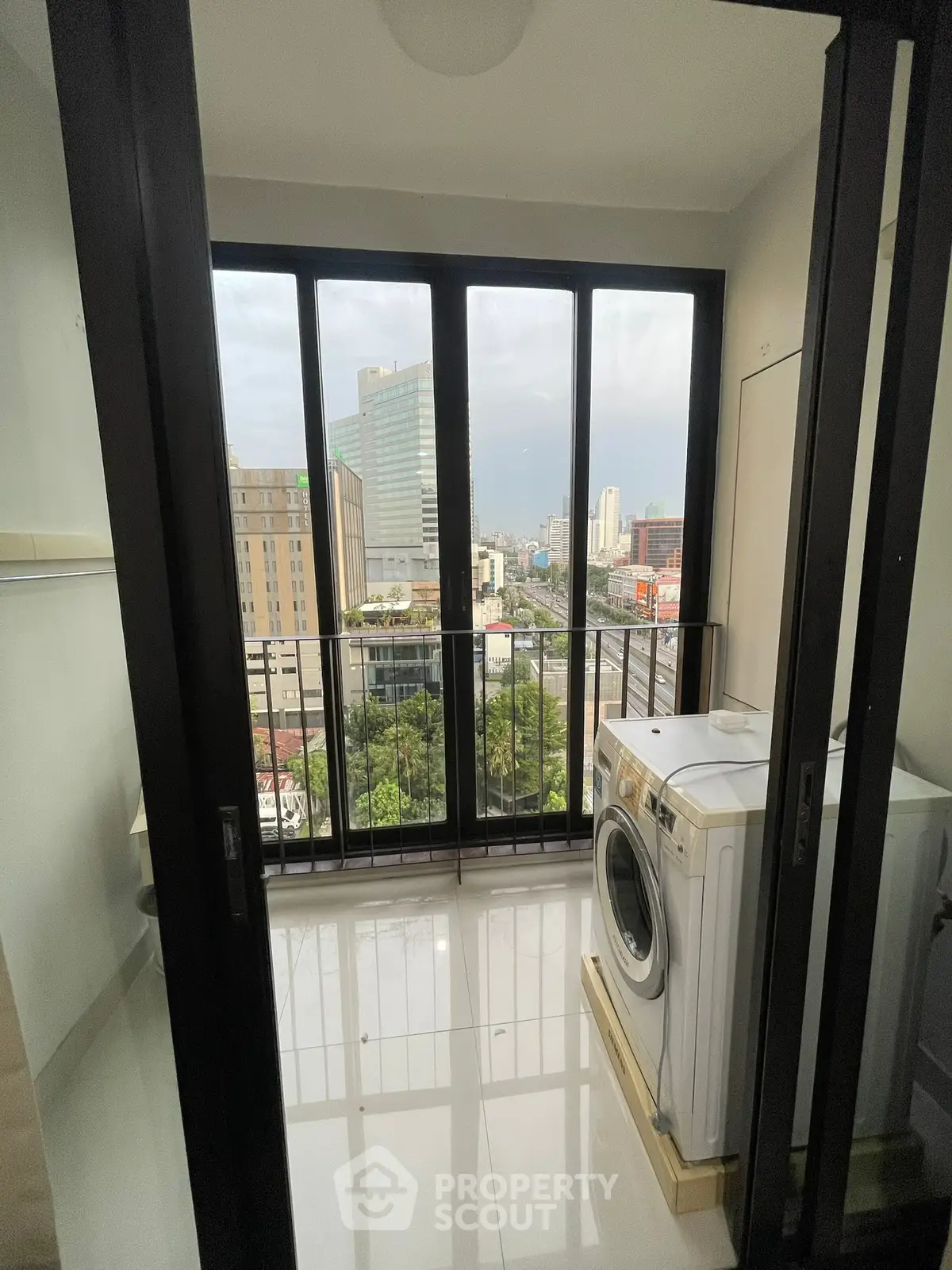 Modern laundry area with city view and washing machine in high-rise apartment.
