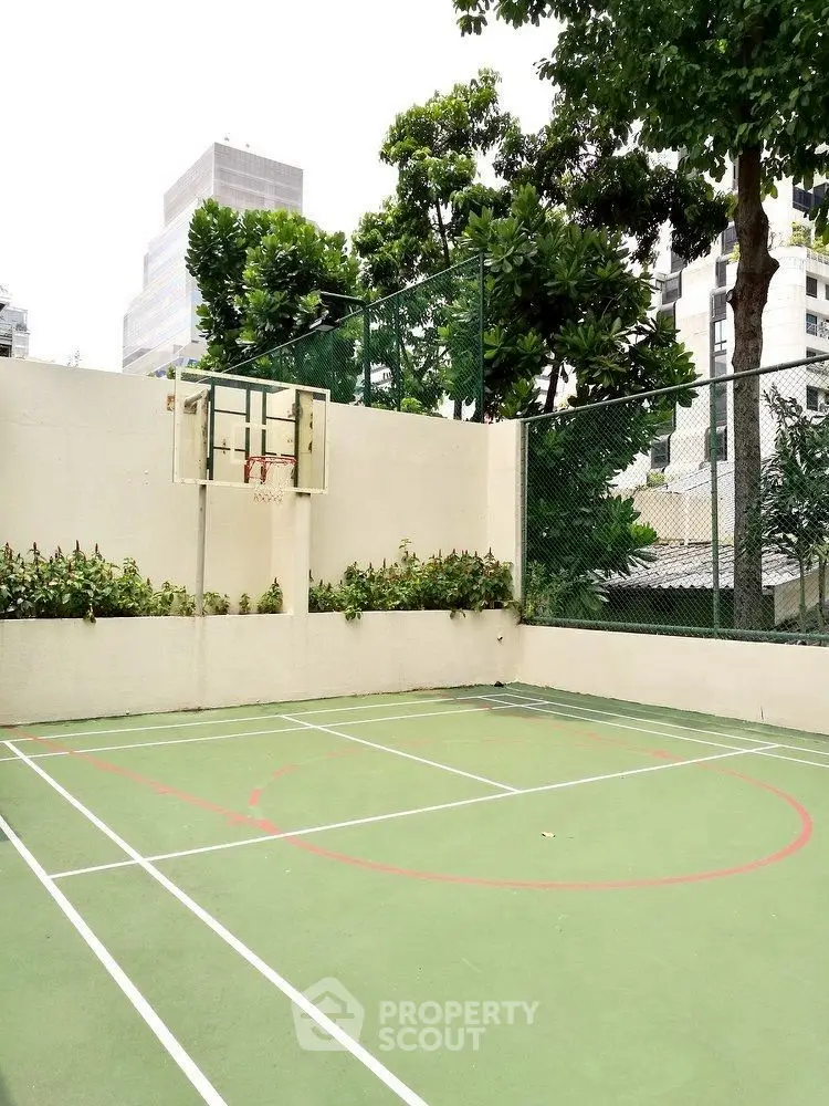 Urban outdoor basketball court with lush greenery and cityscape backdrop