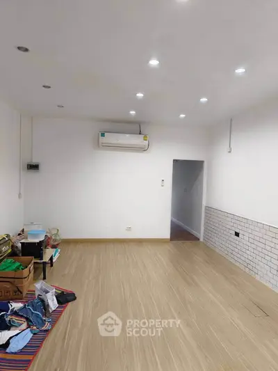 Spacious room with wooden flooring and air conditioning, ideal for versatile use.