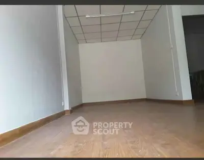 Spacious empty room with wooden flooring and white walls, ideal for customization.