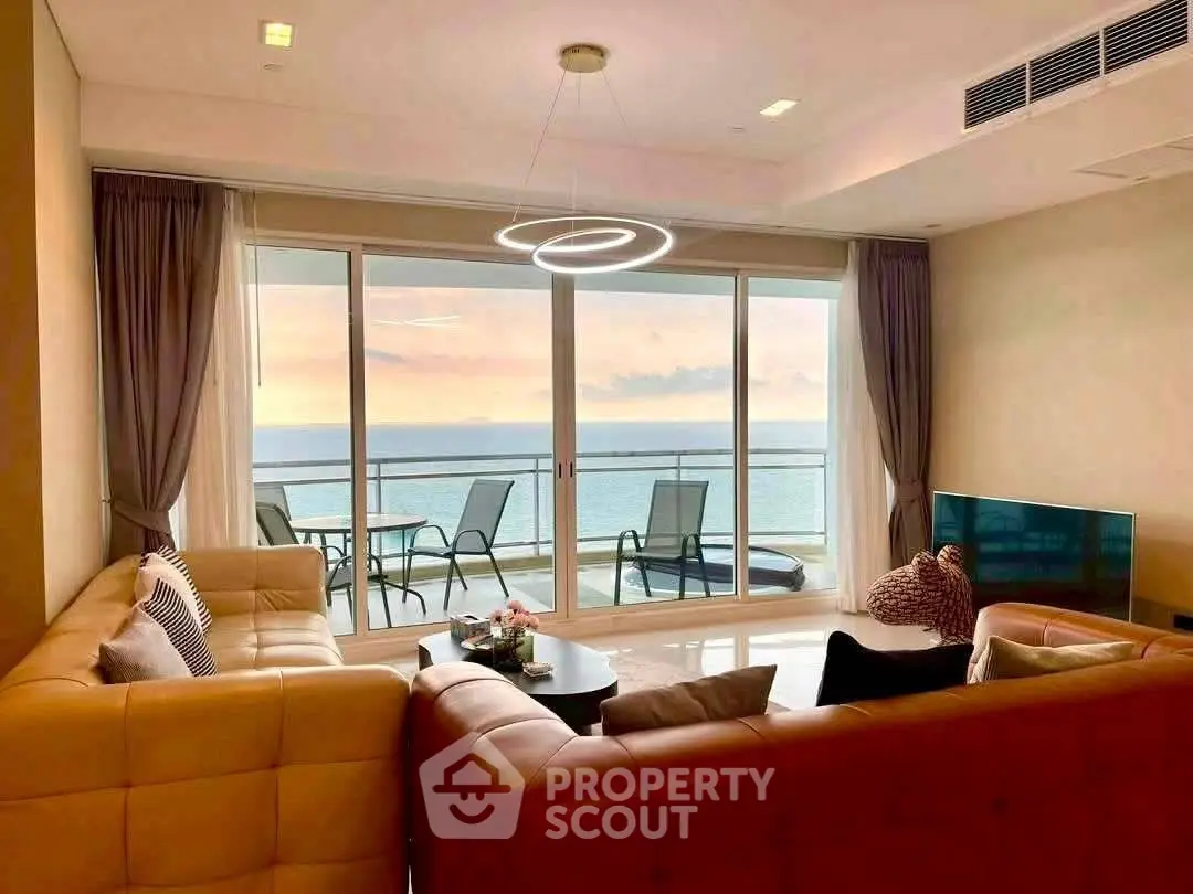 Luxurious living room with ocean view and modern decor, featuring large windows and elegant lighting.
