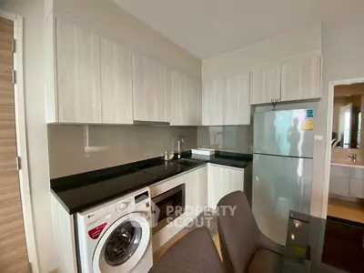 Modern kitchen with sleek cabinets, washing machine, and stainless steel fridge