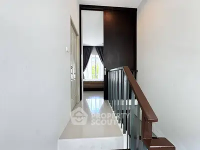 Modern hallway leading to a bright bedroom with large window and elegant curtains.