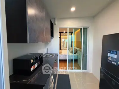 Modern kitchen with sleek appliances and view into cozy bedroom