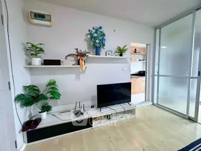 Modern living room with sleek decor and wooden flooring, featuring a TV and stylish shelving.