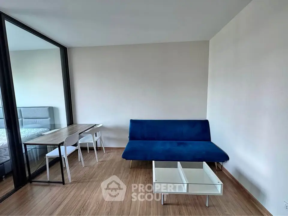 Modern living room with blue sofa and glass coffee table in minimalist apartment