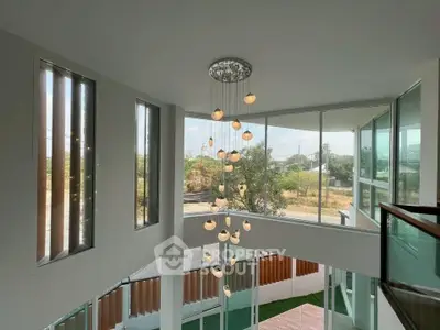 Stunning modern home with large windows and elegant chandelier in a bright, open space.