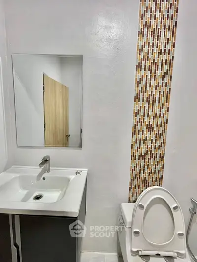 Modern bathroom with stylish mosaic tile accent and sleek fixtures.
