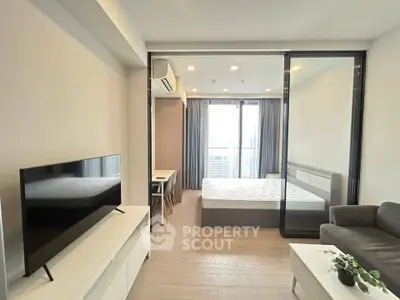Modern studio apartment with open layout, featuring a cozy living area and a bright bedroom with large windows.