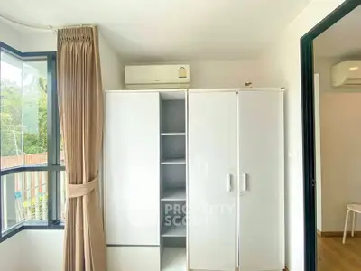 Bright bedroom with large window and modern white wardrobe