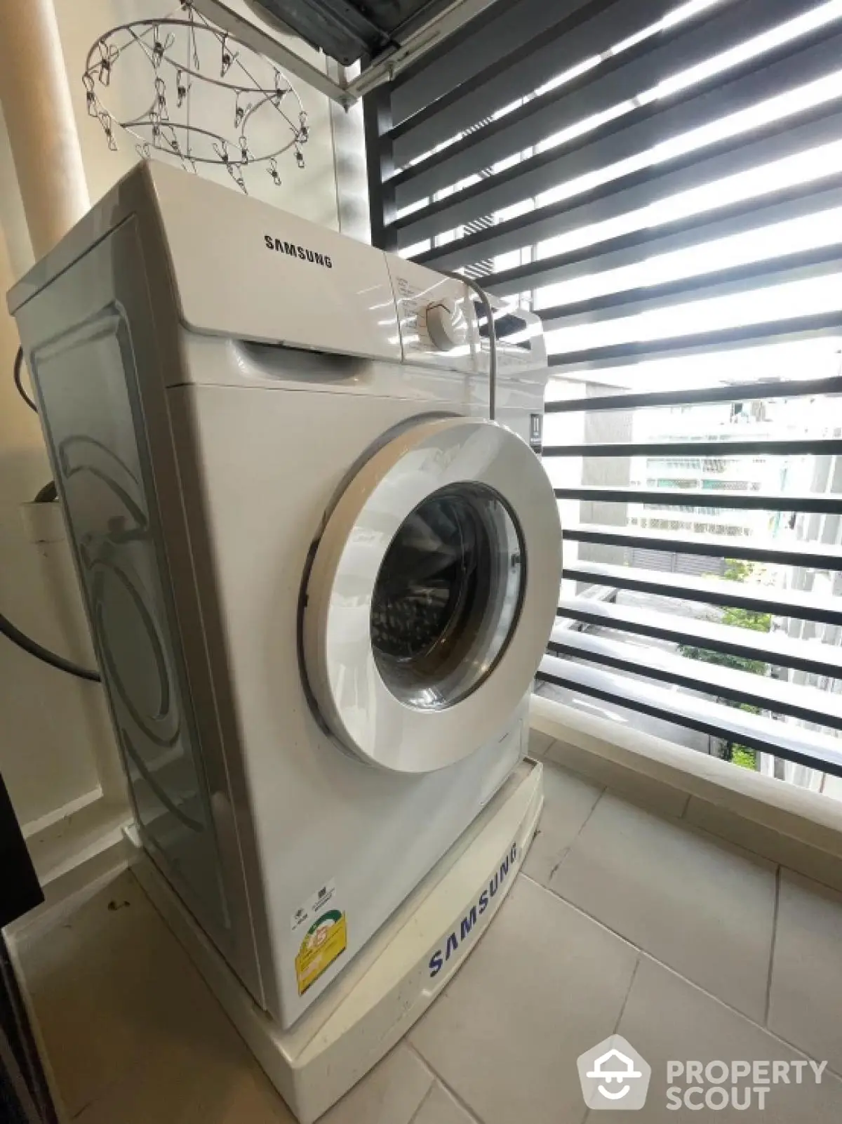 Modern Samsung washing machine in a bright laundry area with stylish blinds.