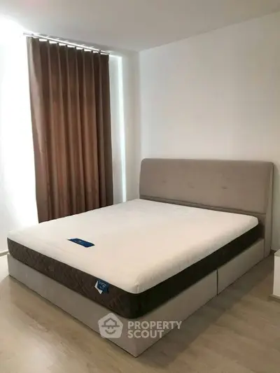 Spacious bedroom with modern bed and elegant curtains, perfect for relaxation.