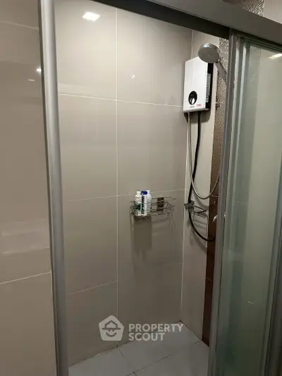 Modern bathroom shower area with glass door and water heater
