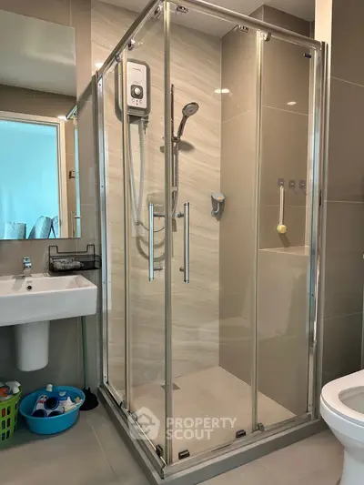 Modern bathroom with glass shower enclosure and sleek fixtures in a contemporary apartment.