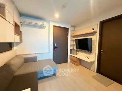 Modern living room with sleek furniture and wall-mounted TV in cozy apartment.