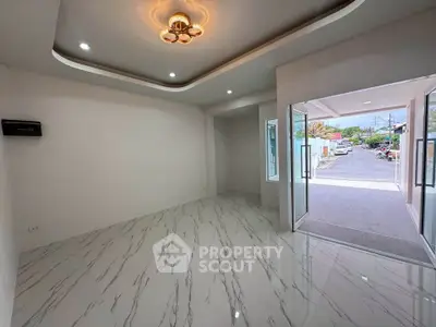 Spacious modern living room with elegant lighting and open view to the street, featuring sleek marble flooring.