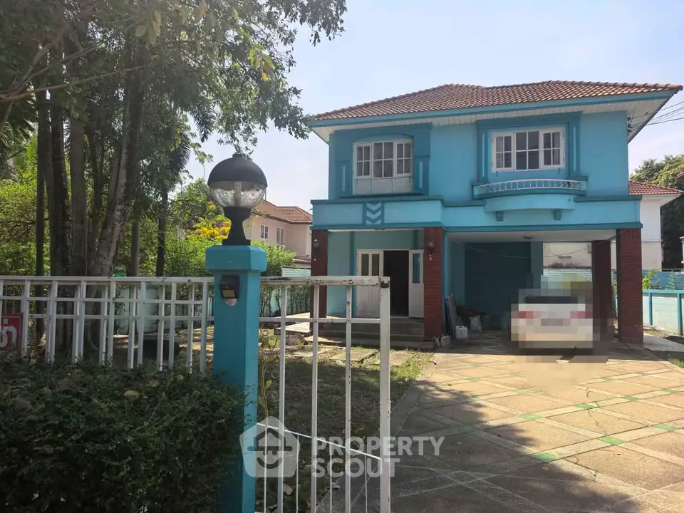 Charming two-story blue house with spacious driveway and lush greenery, perfect for family living.