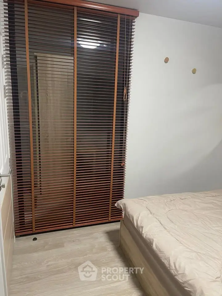 Cozy bedroom with wooden blinds and minimalist decor, perfect for a peaceful retreat.