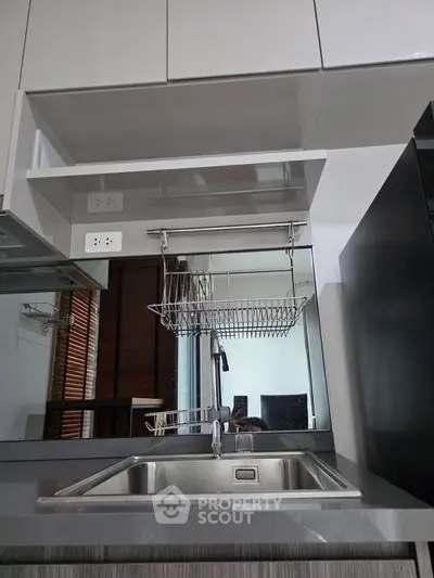 Modern kitchen with sleek cabinetry and stainless steel sink, featuring a convenient dish rack and contemporary design.