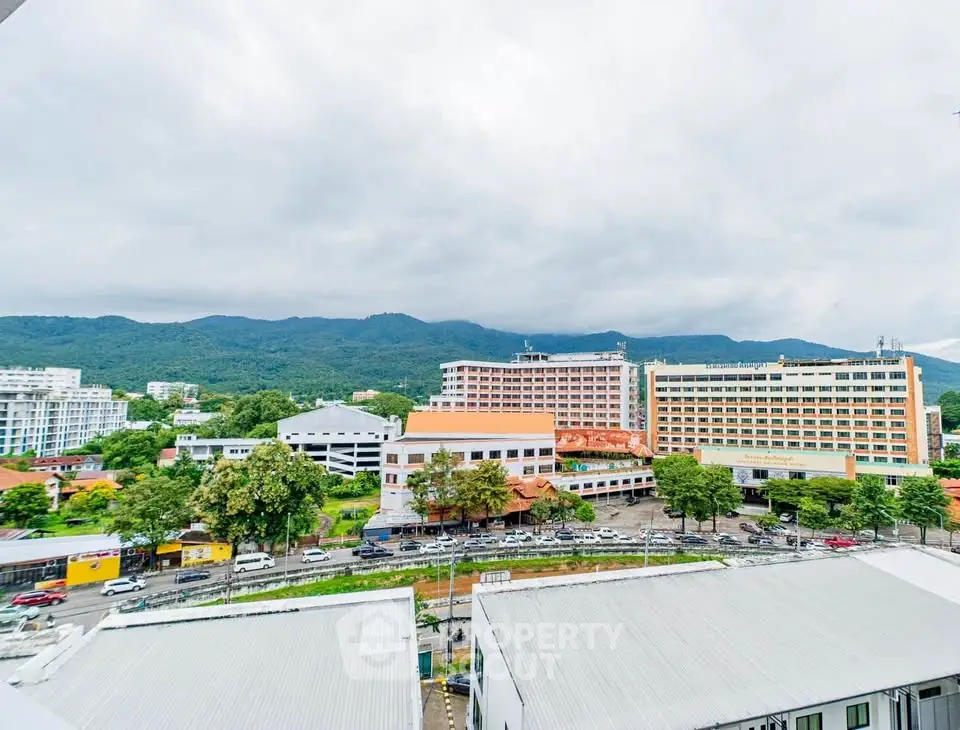 Scenic cityscape view with mountains and buildings under a cloudy sky.