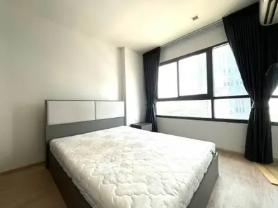 Spacious bedroom with large windows and modern decor in a high-rise apartment.