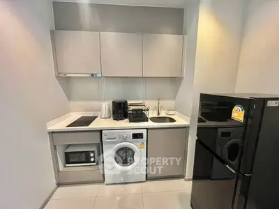 Modern compact kitchen with appliances including washing machine and fridge in sleek design.