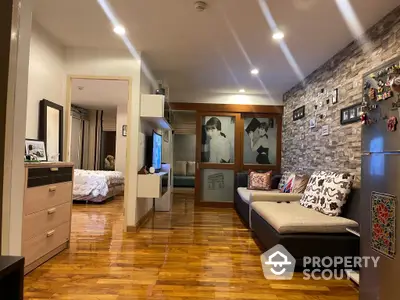 Cozy and modern living room with glossy hardwood floors, stylish stone accent wall, and contemporary furnishings, leading to a serene bedroom.