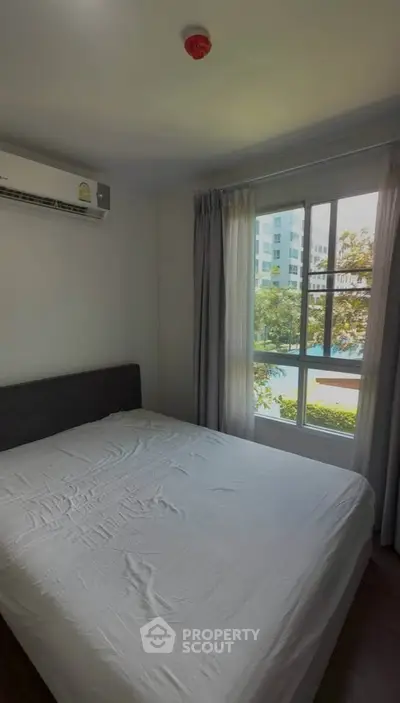 Cozy bedroom with large window and air conditioning in modern apartment
